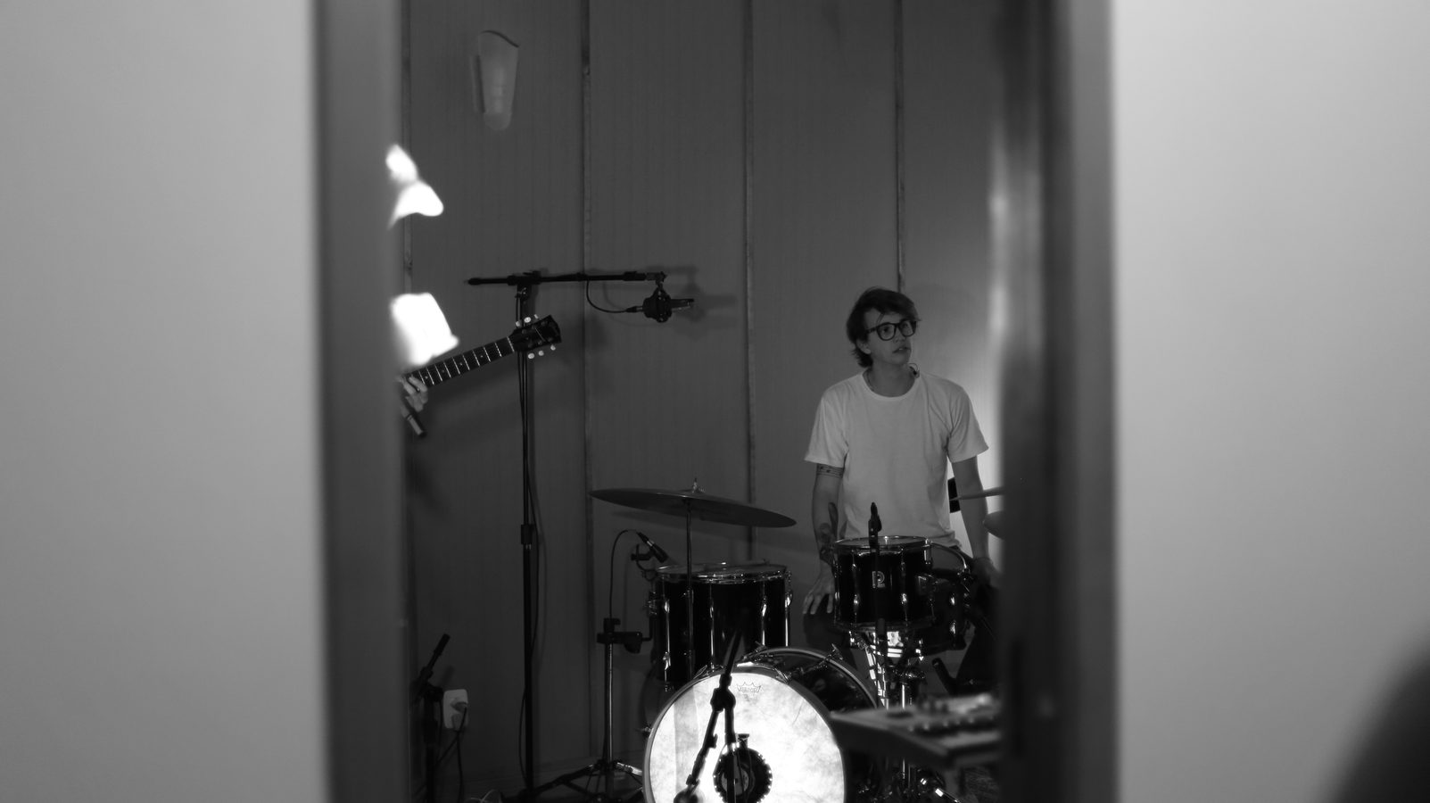 The drummer seen through a half-open door during the session.