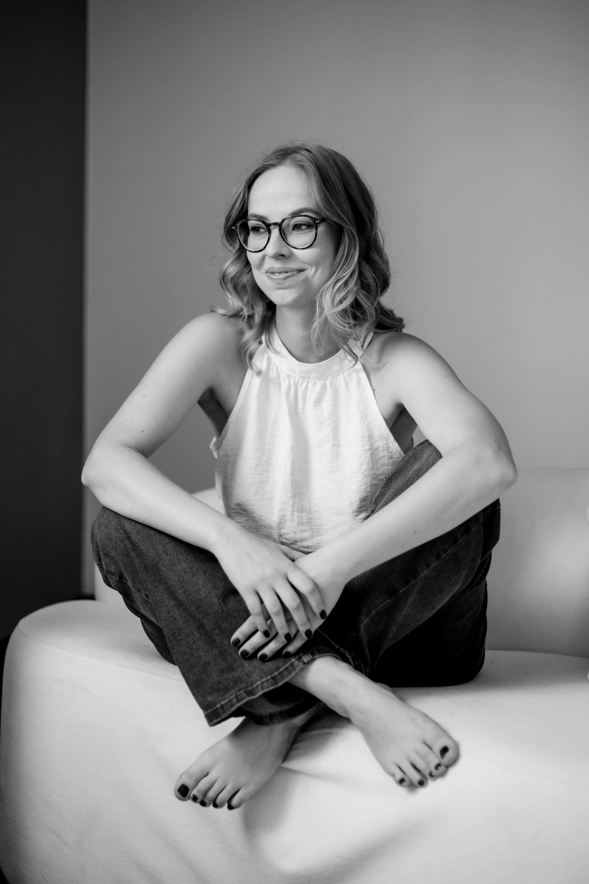 Júlia de Andrade sitting at home, looking away, smiling.